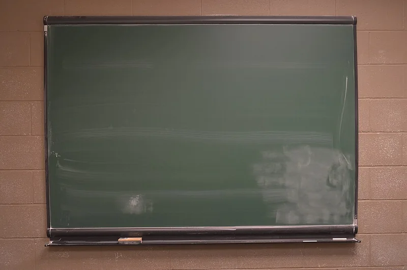 Blank framed green chalkboard with a duster